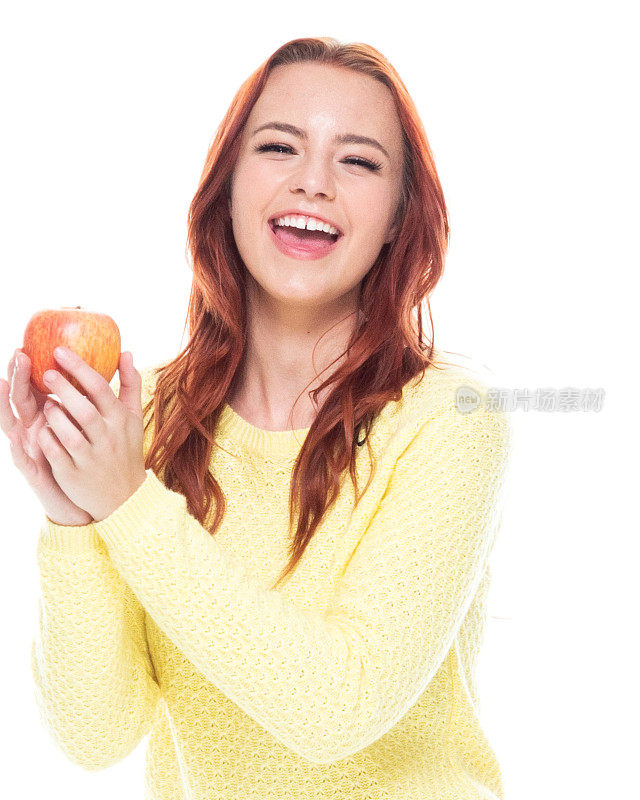腰部以上的18-19岁美丽的红发白人年轻女性十几岁的女孩在白色的背景穿着牛仔裤/开襟毛衣谁是微笑/快乐/愉快谁是出汗/苹果-水果/橙子-水果/香蕉/葡萄